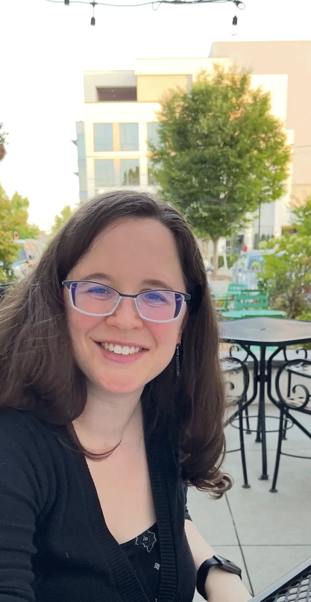 Smiling woman with glasses at outdoor cafe and looking.