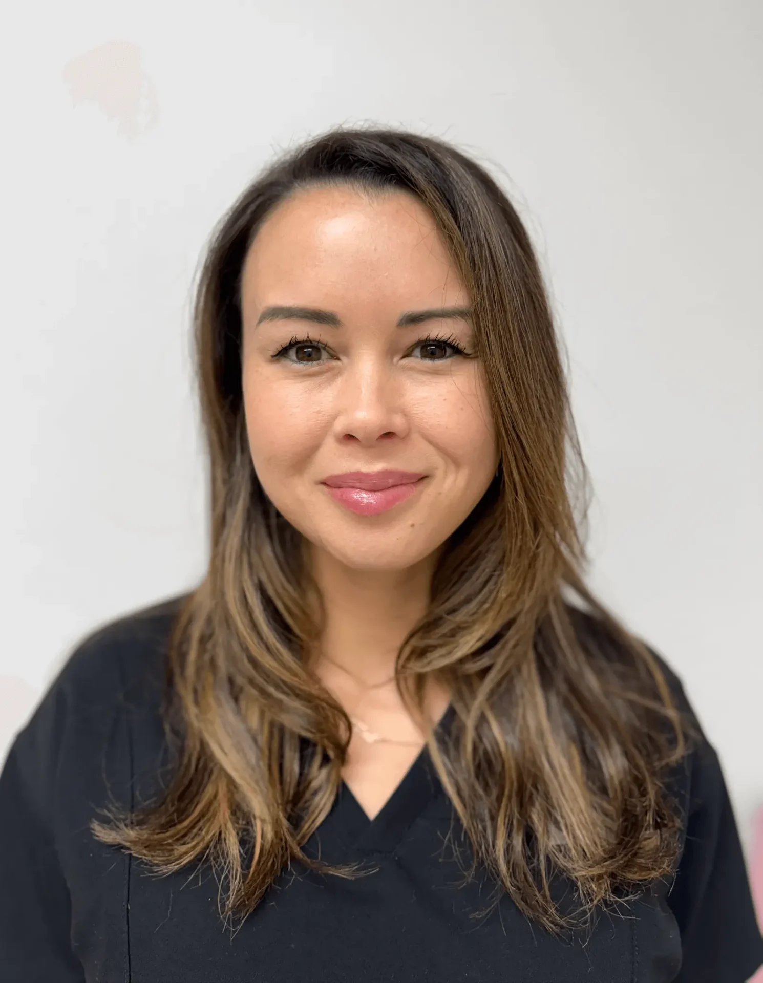 Smiling woman with layered brown hair and black shirt.